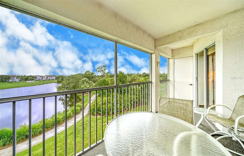 A screened-in balcony overlooks a pond and green space with a glass-topped table and chairs — 9330 CLUBSIDE CIRCLE UNIT 3306, SARASOTA, FL