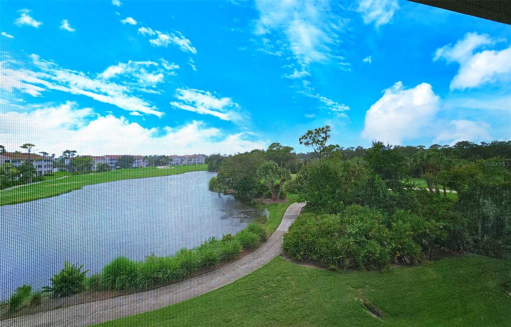 A view of a lake, walking path, and surrounding trees seen through a screen enclosure — 9330 CLUBSIDE CIRCLE UNIT 3306, SARASOTA, FL