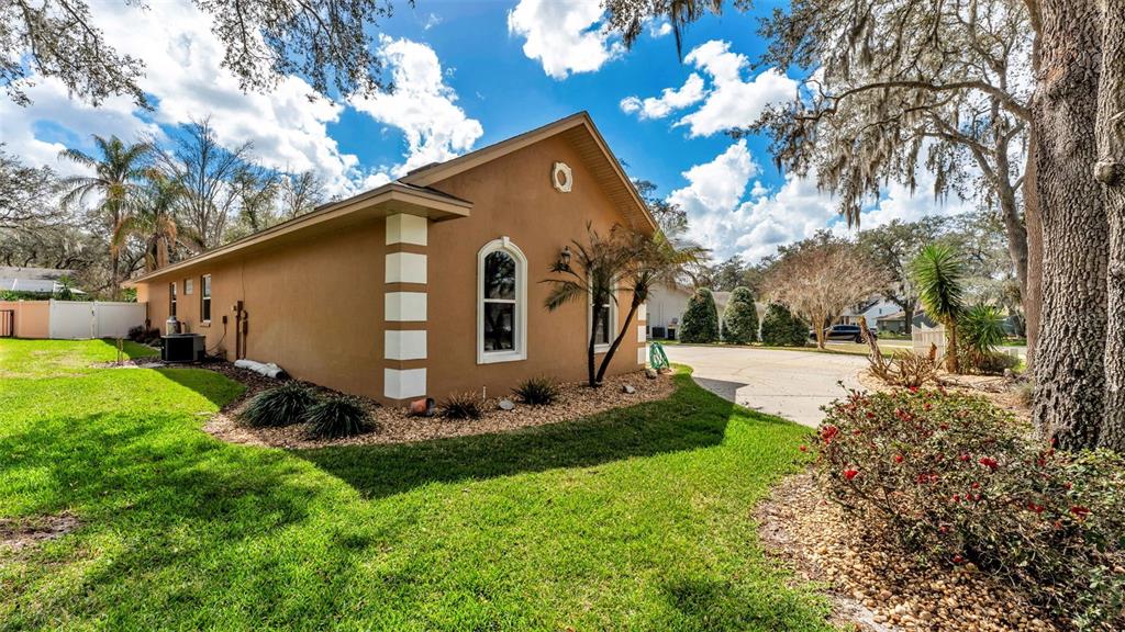 A tan house with white corner accents and a single window sits on a lawn — 1603 SIR HENRYS TRAIL, LAKELAND, FL