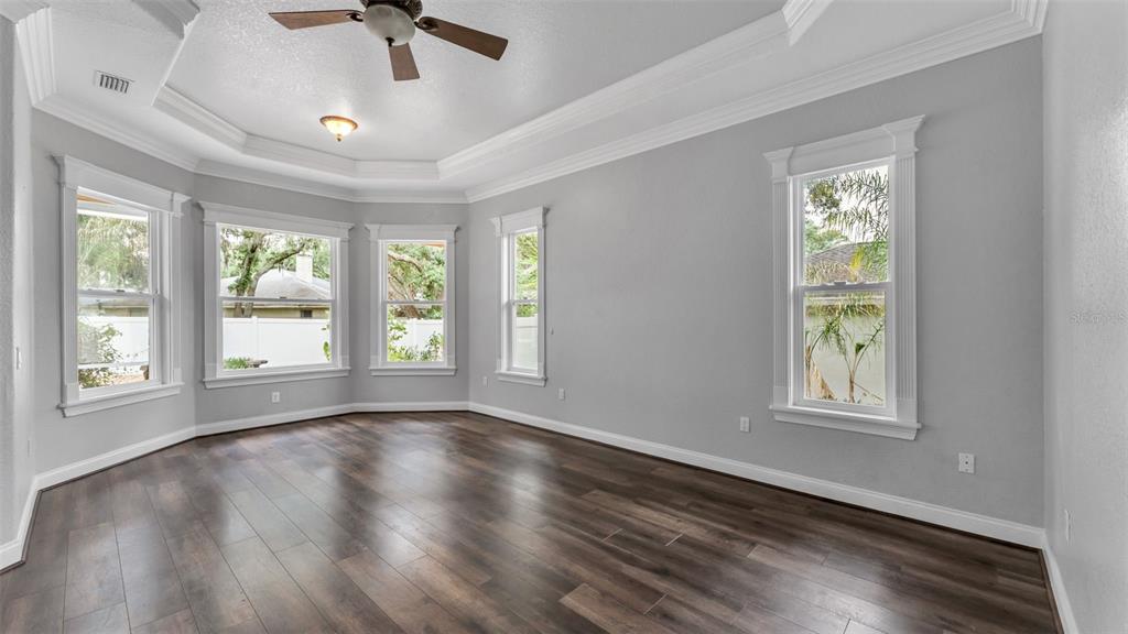 An empty room with gray walls, dark wood flooring, and a bay window area — 1603 SIR HENRYS TRAIL, LAKELAND, FL