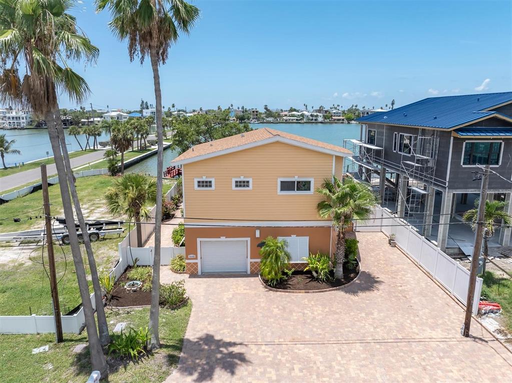 An aerial view of a two-story house with a paved driveway and a waterfront backyard — 16102 4TH STREET E, REDINGTON BEACH, FL