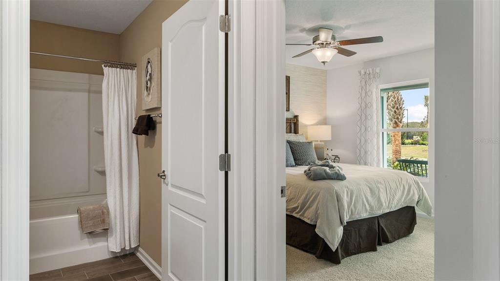 A bathroom with a shower-tub combo opens into a bedroom with a ceiling fan — 146 GREENWOOD DRIVE, PALM COAST, FL