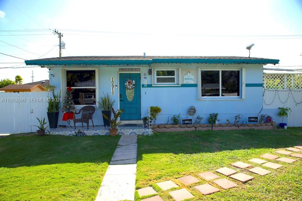 A single-story light blue house features a teal front door and a concrete walkway — 10910 SW 217th Ter, Miami FL 33170, MIAMI, FL