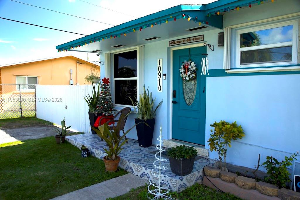 A light blue house exterior features a teal front door, patterned porch tiles, and plants — 10910 SW 217th Ter, Miami FL 33170, MIAMI, FL