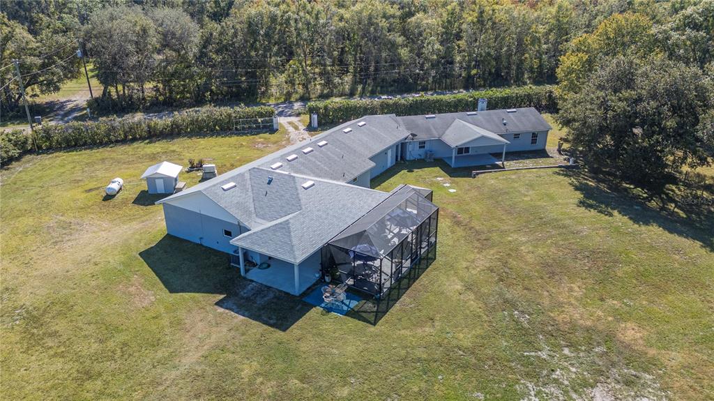 An aerial view shows a sprawling single-story house with a pool enclosure and detached buildings — 2525 RANCHLAND ACRES ROAD, LAKELAND, FL