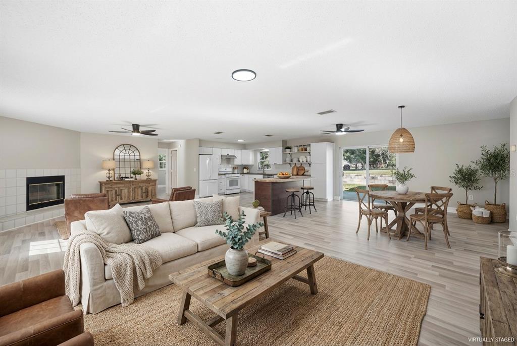 A virtually staged open-concept living room and kitchen with light wood floors and a fireplace — 2525 RANCHLAND ACRES ROAD, LAKELAND, FL