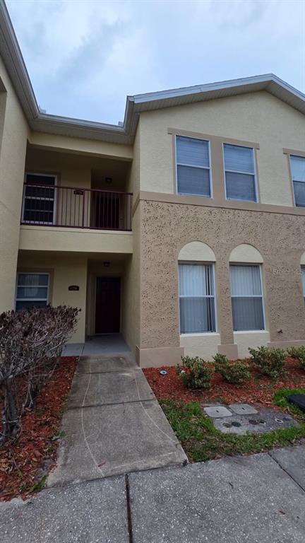 A two-story tan stucco building features a covered entryway, a balcony, and arched windows — 2776 CLUB CORTILE CIRCLE UNIT A, KISSIMMEE, FL