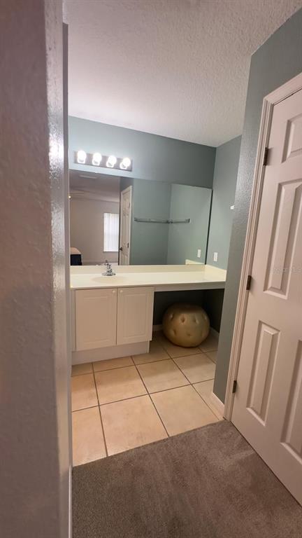 A bathroom vanity with a white cabinet, beige countertop, and a large mirror on blue walls — 2776 CLUB CORTILE CIRCLE UNIT A, KISSIMMEE, FL