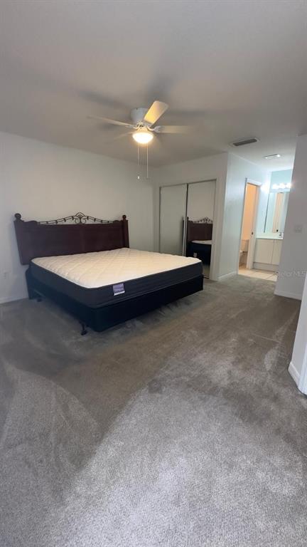 A bedroom features a bed with a dark headboard, carpeted flooring, and a ceiling fan — 2776 CLUB CORTILE CIRCLE UNIT A, KISSIMMEE, FL