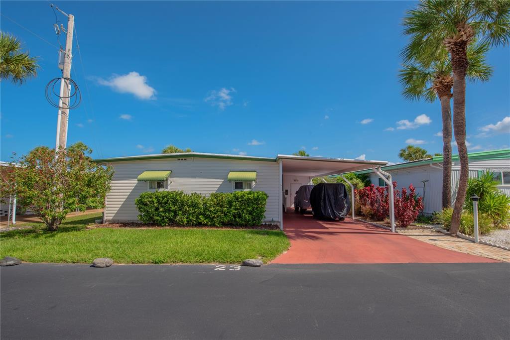 A single-story mobile home with a carport, green awnings, and a red driveway — 4851 W GANDY BOULEVARD UNIT 23C, TAMPA, FL