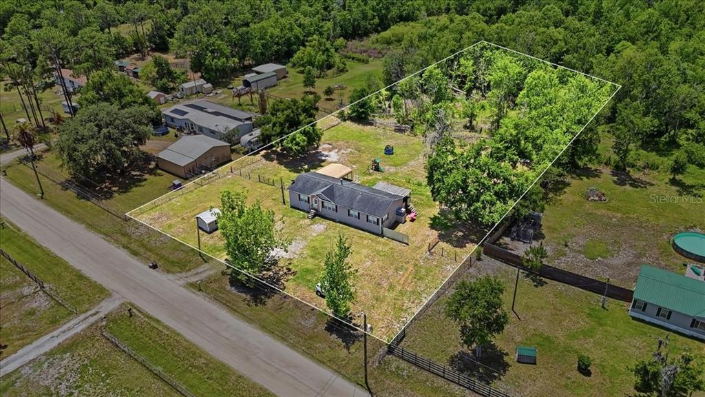 An aerial view shows a single-story house on a large, fenced, grassy lot with trees — 10724 PATHFINDER TRAIL, LAKELAND, FL