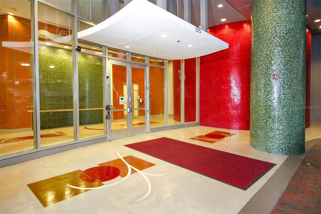 The entrance to a building features a glass door, red and green tiled walls, and a canopy — 155 S COURT AVENUE UNIT 1102, ORLANDO, FL