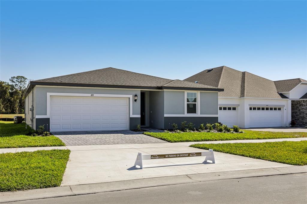 A single-story suburban house with a two-car garage and a paved driveway — 855 SUNSHOWER DRIVE, LADY LAKE, FL