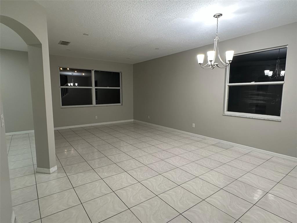 A dining room with light-colored tile flooring, gray walls, and a hanging chandelier — 4743 CHALFONT DRIVE, ORLANDO, FL