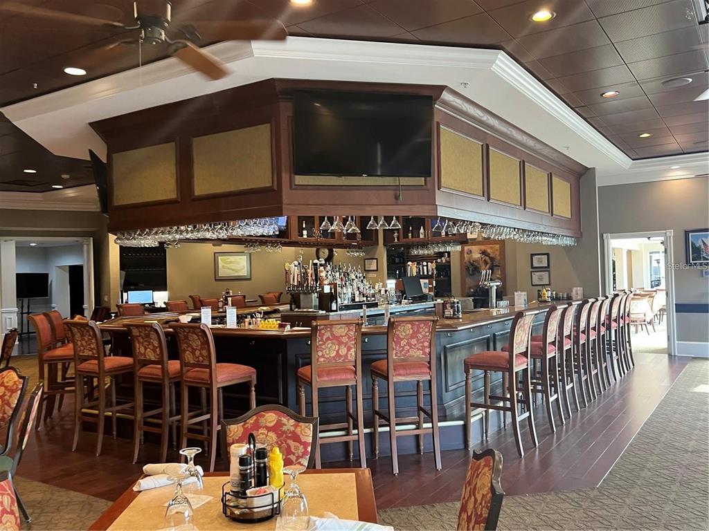 A bar area features a large wooden counter, numerous high-backed chairs, and a ceiling fan — 6501 STONE RIVER ROAD UNIT 309, BRADENTON, FL
