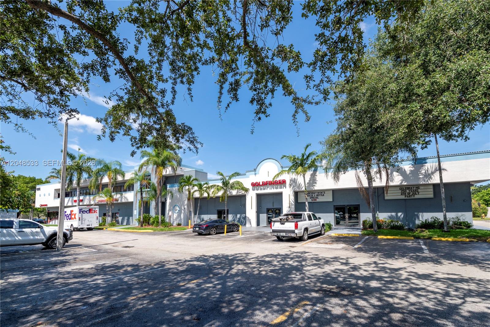 A low-rise commercial building with a parking lot and palm trees under a blue sky — 3801 N University Dr # 320, Sunrise FL 33351, SUNRISE, FL
