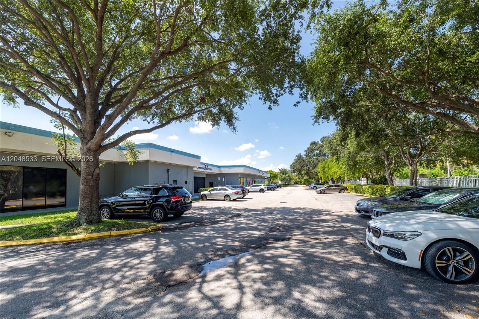 A parking lot with several cars sits in front of a commercial building under trees — 3801 N University Dr # 320, Sunrise FL 33351, SUNRISE, FL