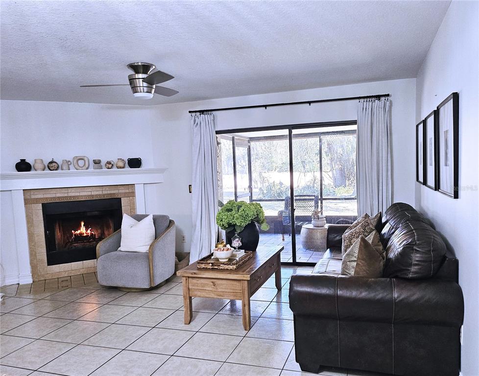 A living room features a fireplace, tile flooring, a leather sofa, and sliding glass doors — 446 CLUB DRIVE, WINTER SPRINGS, FL