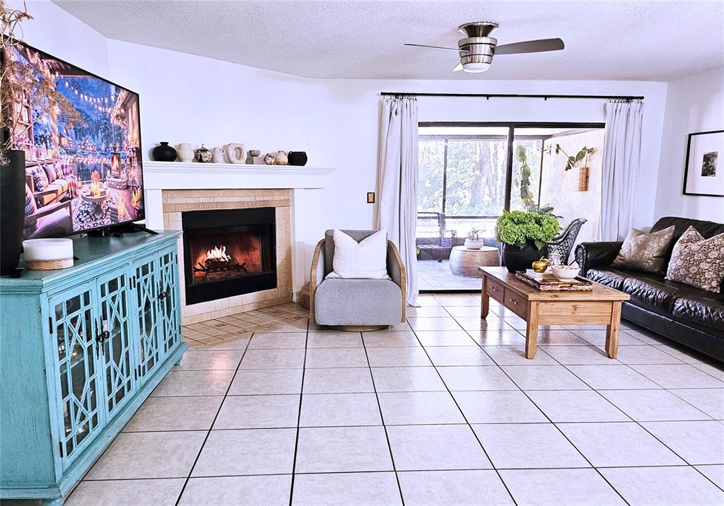 A living room features a fireplace, a blue media console, and a sliding glass door — 446 CLUB DRIVE, WINTER SPRINGS, FL