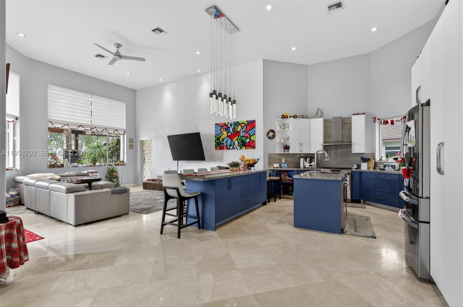 An open-concept kitchen and living area features blue cabinetry, a large island, and tile flooring — 104 Dockside Cir, Weston FL 33327, WESTON, FL