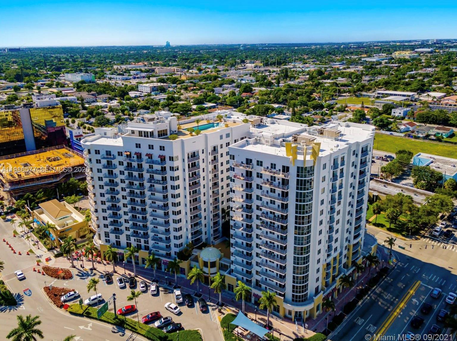 An aerial view shows a multi-story white apartment building with a rooftop pool and parking — 1830 Radius Dr # 1222, Hollywood FL 33020, HOLLYWOOD, FL