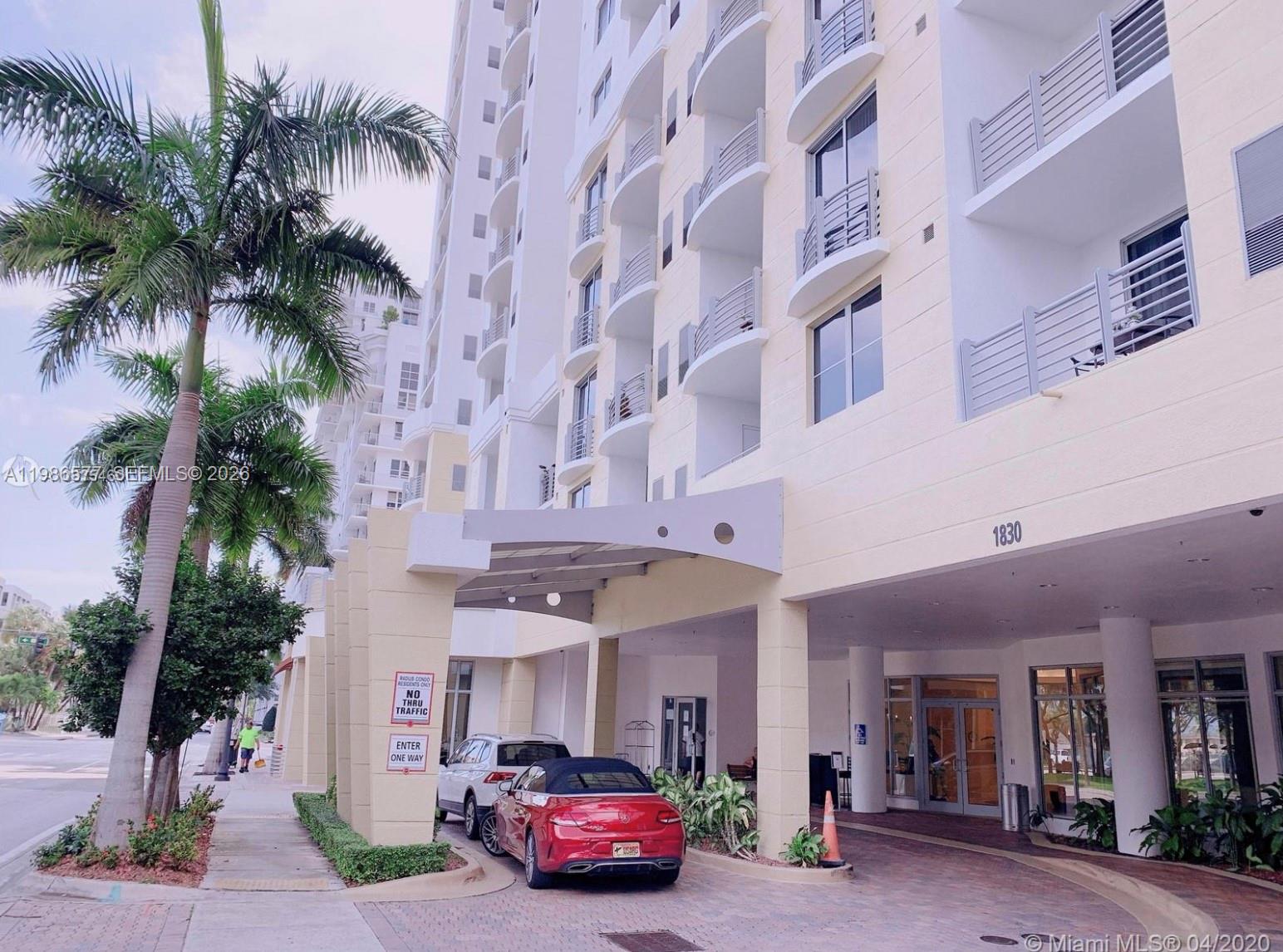 The exterior of a multi-story residential building features a covered entrance with a red car — 1830 Radius Dr # 1222, Hollywood FL 33020, HOLLYWOOD, FL