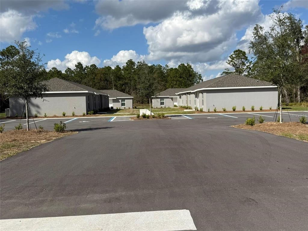 A paved parking lot sits in front of two gray, single-story residential buildings — 9541 N TRAVIS DRIVE UNIT A, CITRUS SPRINGS, FL