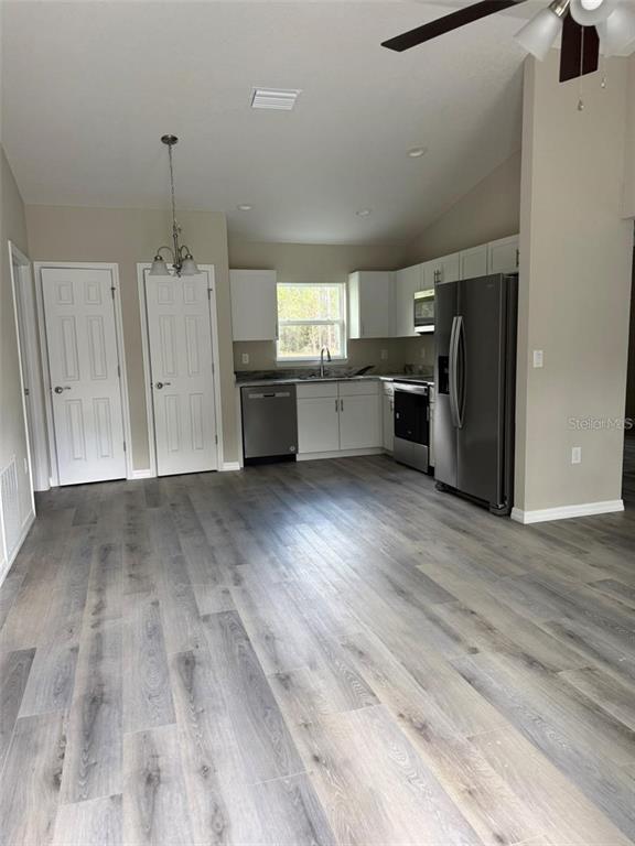 A kitchen features white cabinets, stainless steel appliances, and gray wood-look flooring — 9541 N TRAVIS DRIVE UNIT A, CITRUS SPRINGS, FL