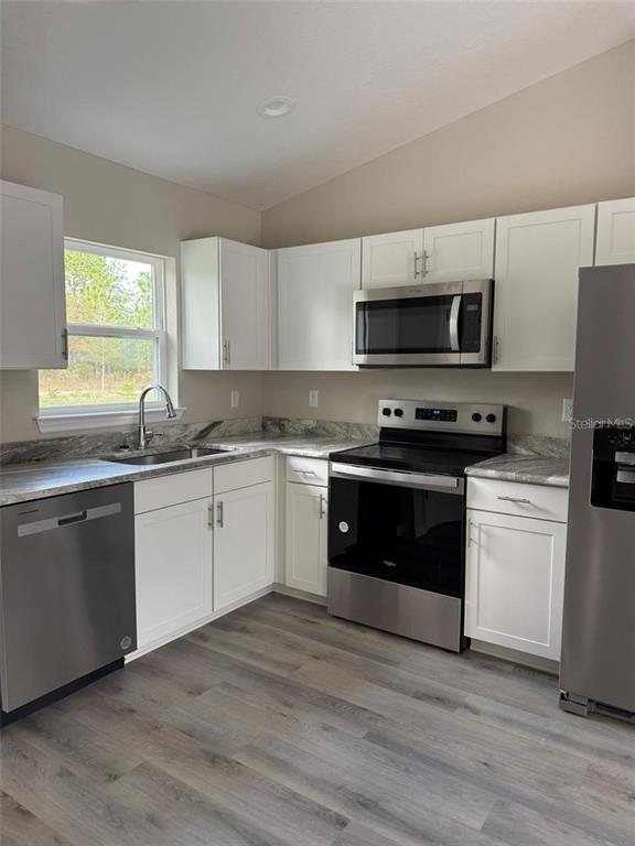 A kitchen features white cabinets, stainless steel appliances, and wood-look flooring — 9541 N TRAVIS DRIVE UNIT A, CITRUS SPRINGS, FL