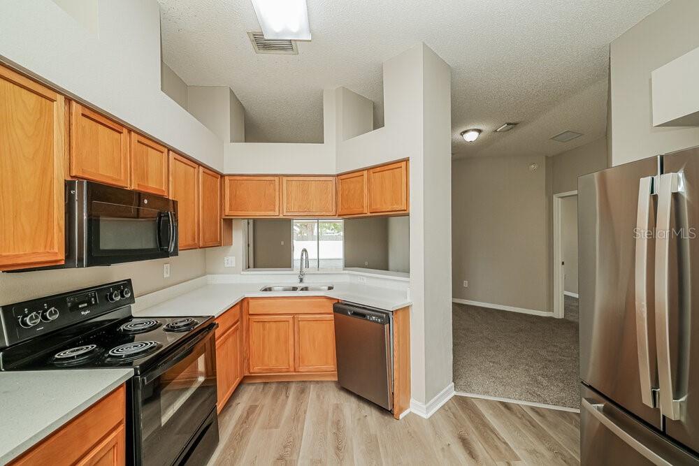 A kitchen with wood cabinets, stainless steel appliances, and light-colored countertops — 11025 WHITTNEY CHASE DRIVE, RIVERVIEW, FL