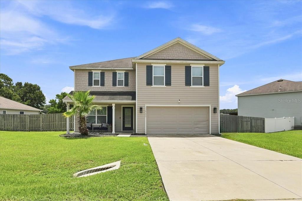 A two-story suburban house features beige siding, a front porch, and an attached two-car garage — 22885 NW 197TH PLACE, HIGH SPRINGS, FL