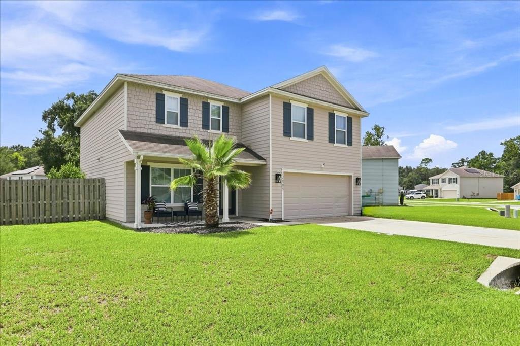 A two-story suburban house with beige siding, a two-car garage, and a front lawn — 22885 NW 197TH PLACE, HIGH SPRINGS, FL