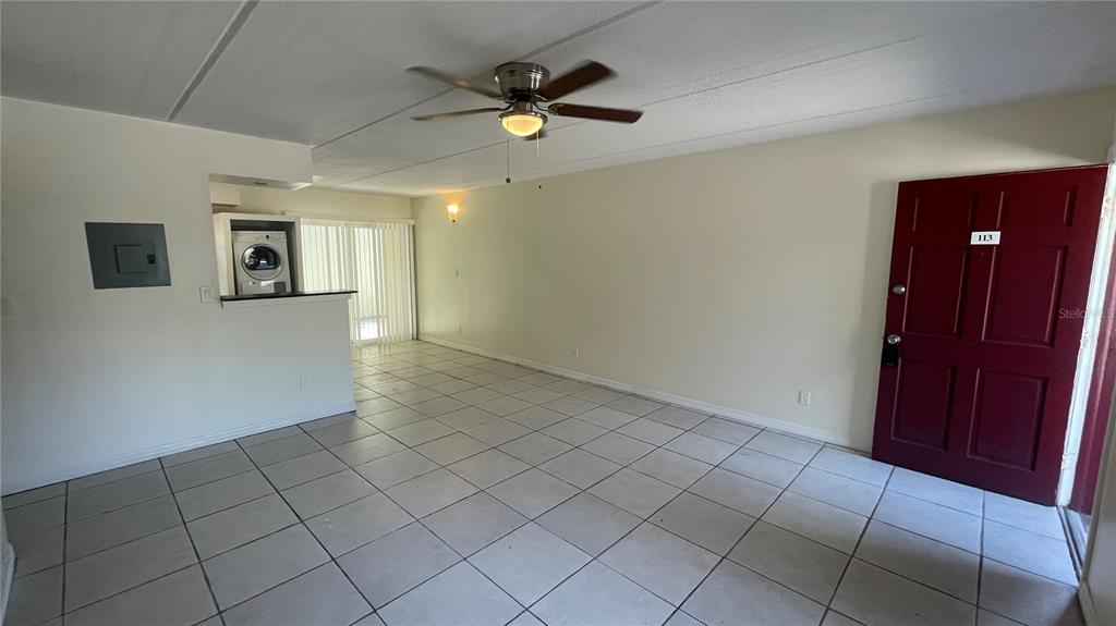 An interior view of a room with tiled floors, a ceiling fan, and a red door — 2800 E 113TH AVENUE UNIT B2113, TAMPA, FL