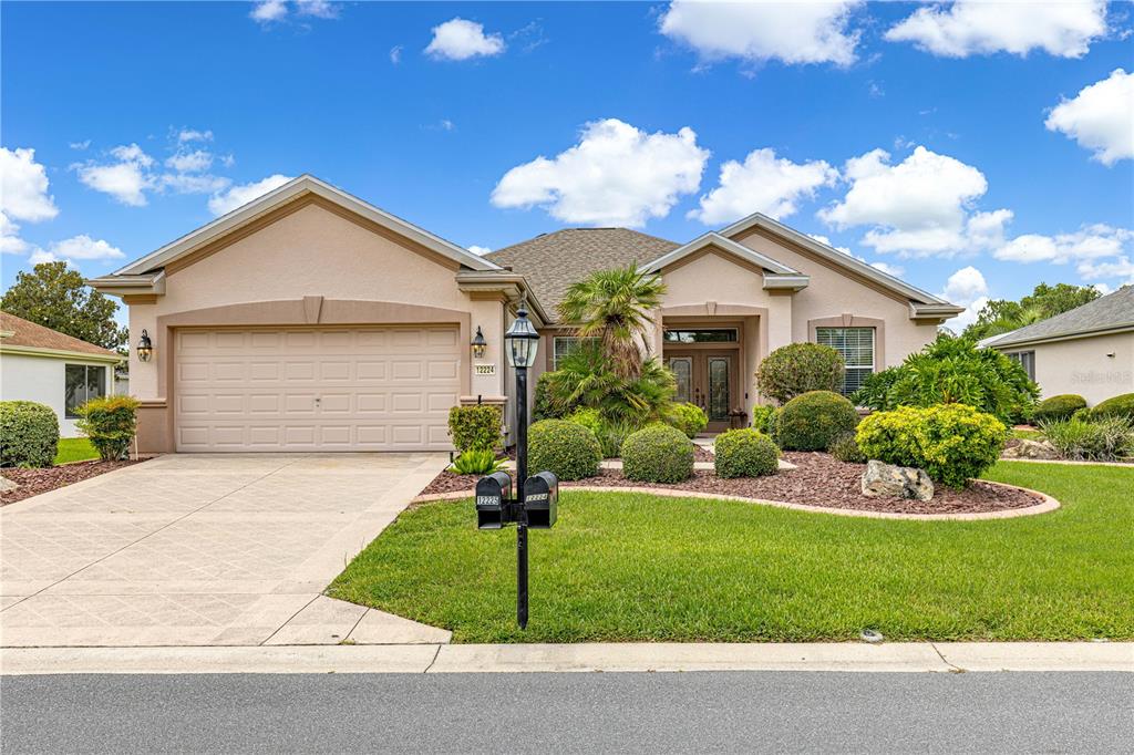 A single-story suburban house features a two-car garage, a landscaped front yard, and double doors — 12224 SE 91ST AVENUE, SUMMERFIELD, FL