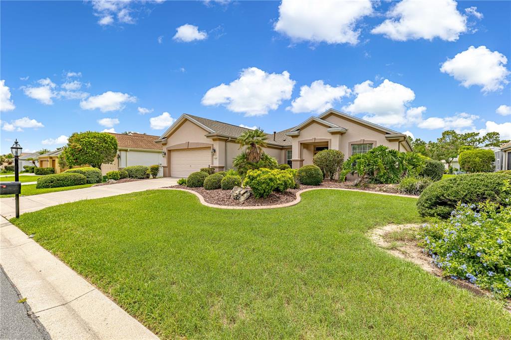 A single-story house with a beige exterior, a two-car garage, and a landscaped front yard — 12224 SE 91ST AVENUE, SUMMERFIELD, FL