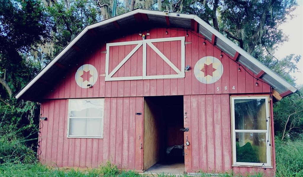 A red barn-style structure with a central doorway, two windows, and two decorative star emblems — 564 SW OAK AVENUE W, SEBRING, FL
