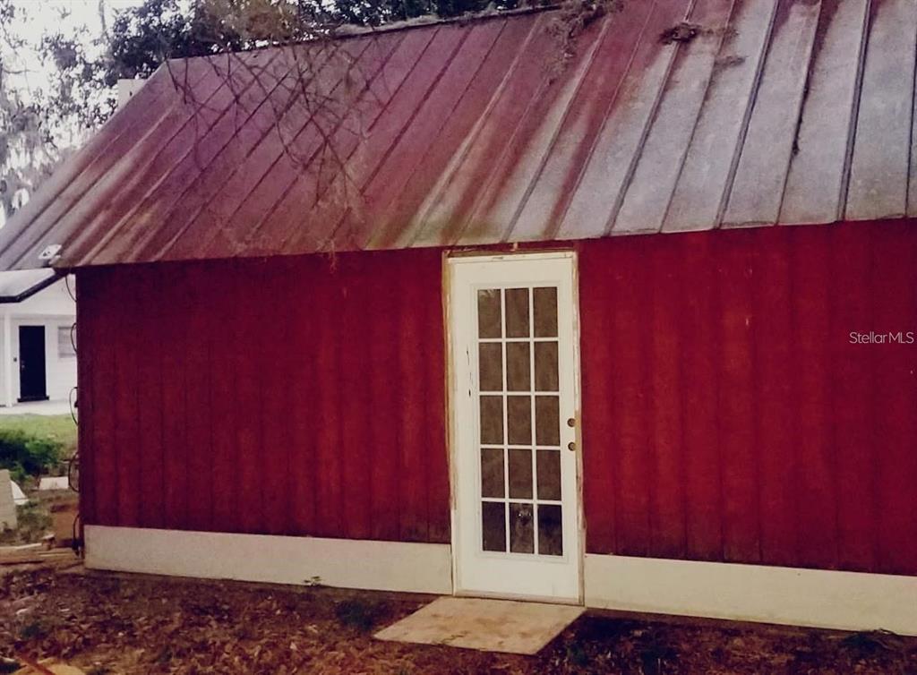 A red barn-style building with a metal roof and a white glass-paneled door — 564 SW OAK AVENUE W, SEBRING, FL