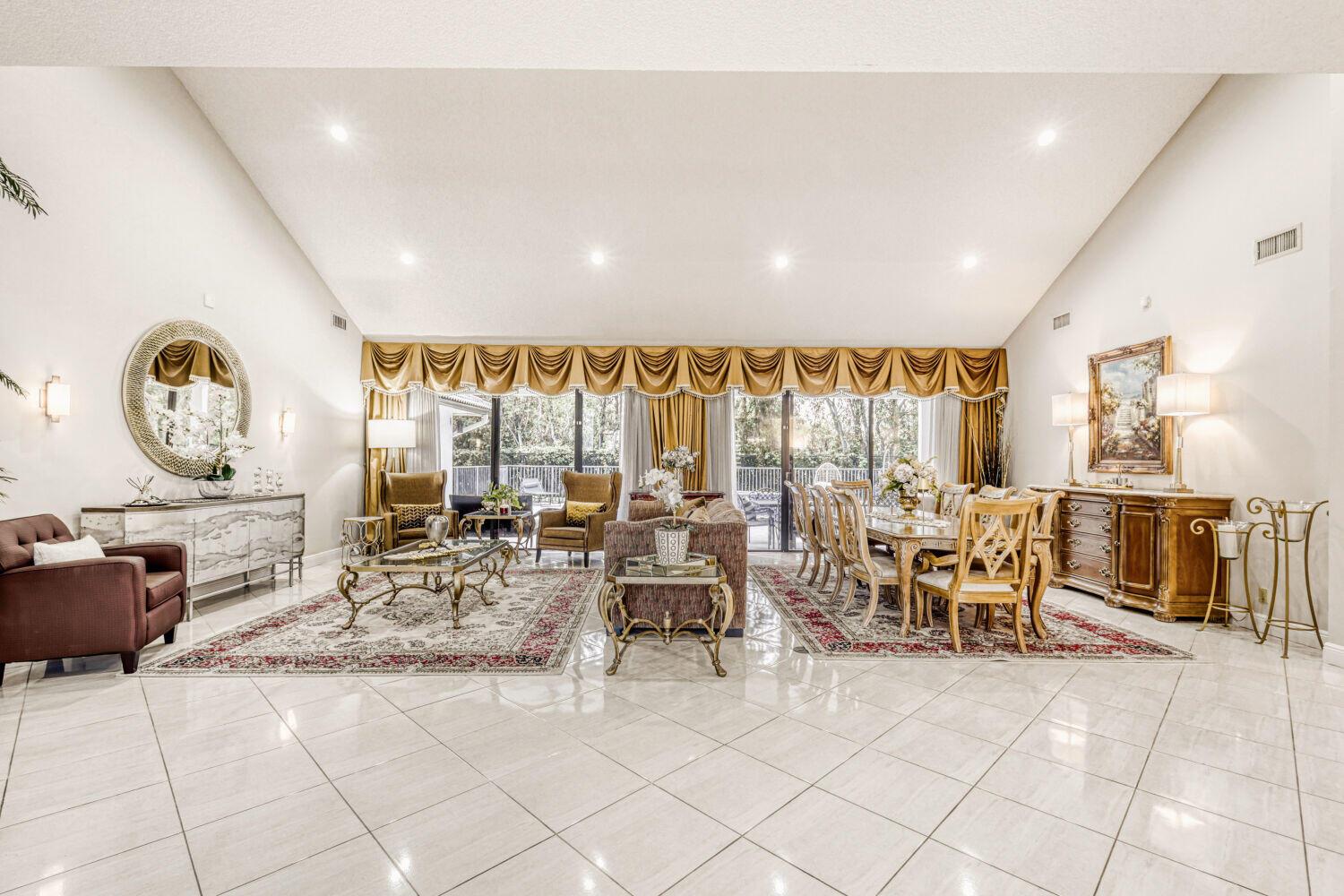 A spacious living and dining room with vaulted ceilings, tile floors, and gold-toned window treatments — 10273 St Andrews Road, Boynton Beach FL 33436, BOYNTON BEACH, FL