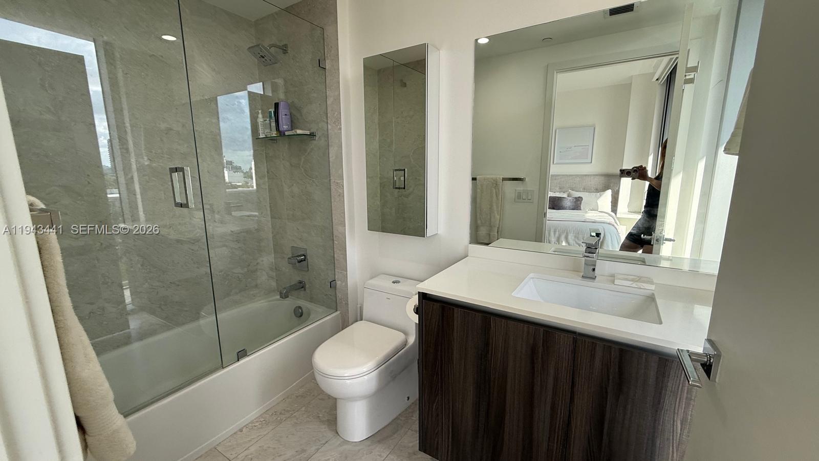 A modern bathroom features a glass-enclosed shower, a white vanity, and a toilet — 488 NE 18th St # 700, Miami FL 33132, MIAMI, FL
