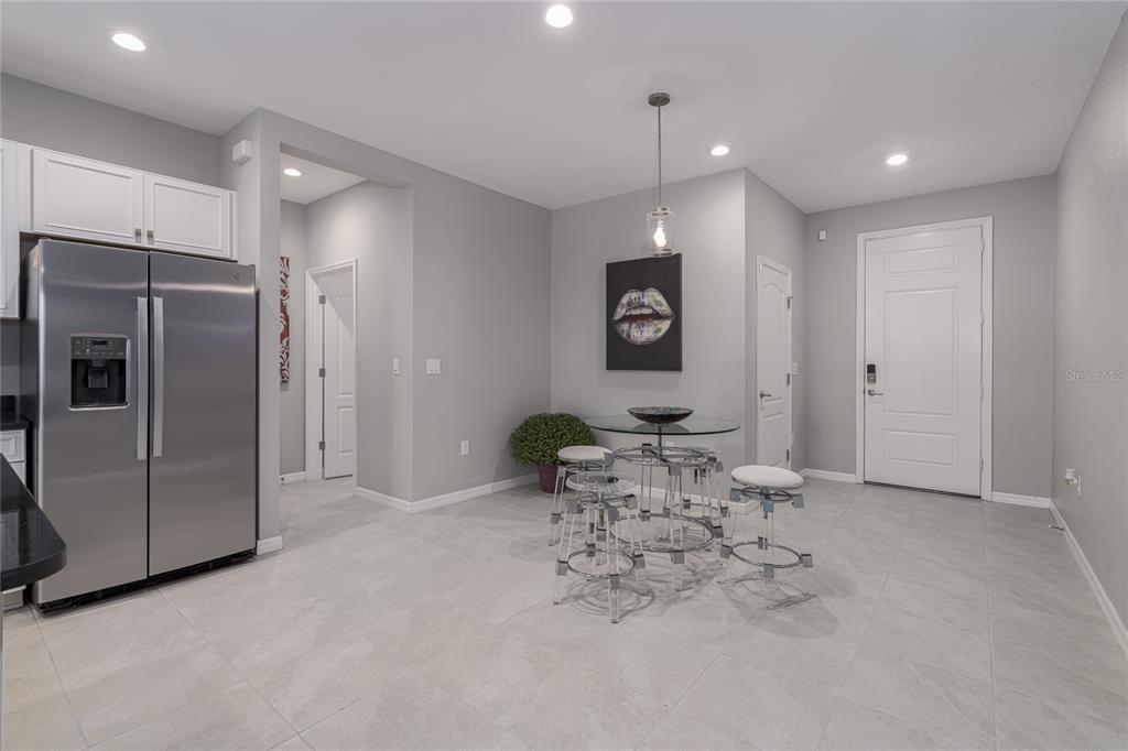 A kitchen and dining area featuring a stainless steel refrigerator, tile flooring, and glass table — 8518 CANYON CREEK TRAIL, PARRISH, FL