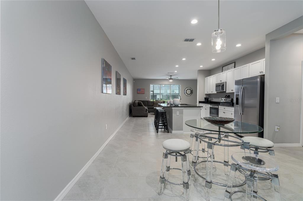 An open-concept kitchen and living area features light gray walls, tile flooring, and stainless appliances — 8518 CANYON CREEK TRAIL, PARRISH, FL