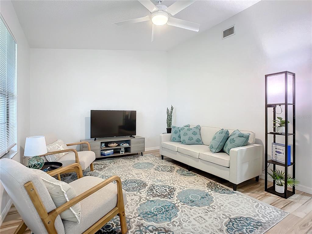 A living room features a white sofa, two armchairs, a television console, and a patterned rug — 840 CENTER AVENUE UNIT 520, HOLLY HILL, FL