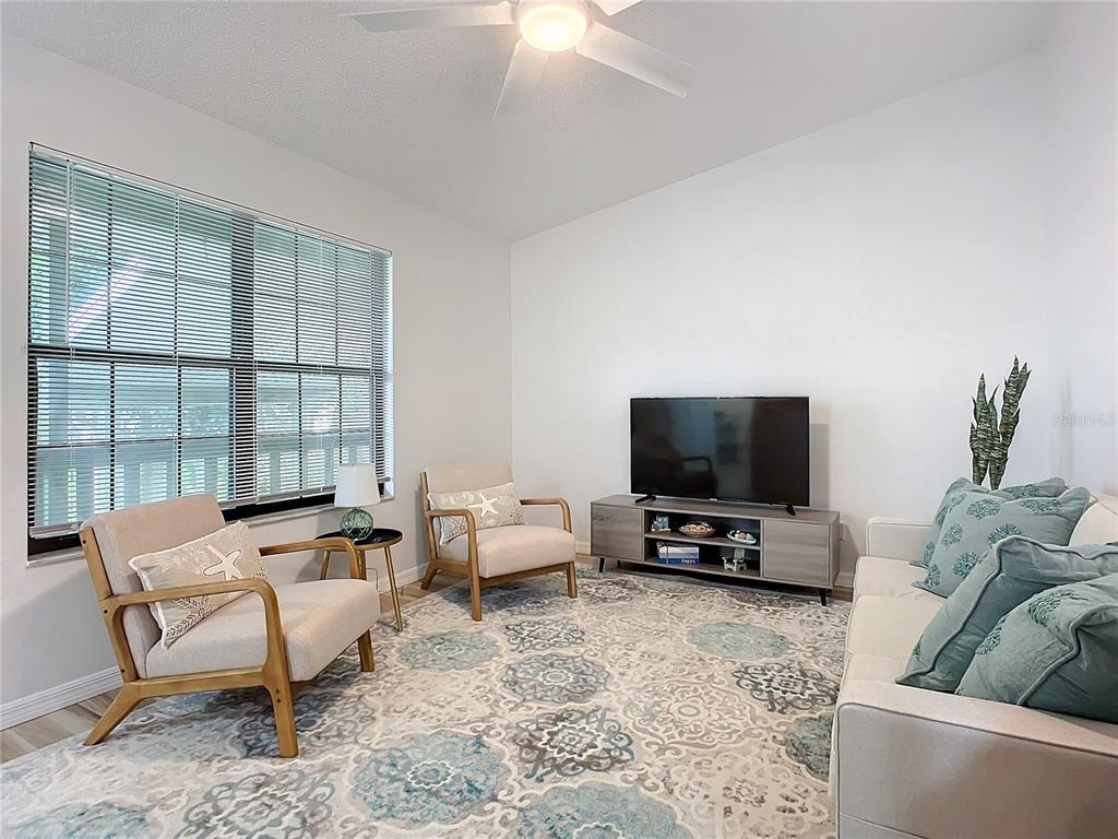 A living room features a patterned area rug, two armchairs, a sofa, and a television — 840 CENTER AVENUE UNIT 520, HOLLY HILL, FL