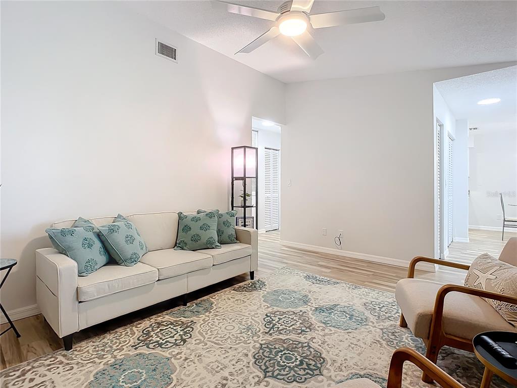 A living room features a white sofa, patterned area rug, and a ceiling fan — 840 CENTER AVENUE UNIT 520, HOLLY HILL, FL
