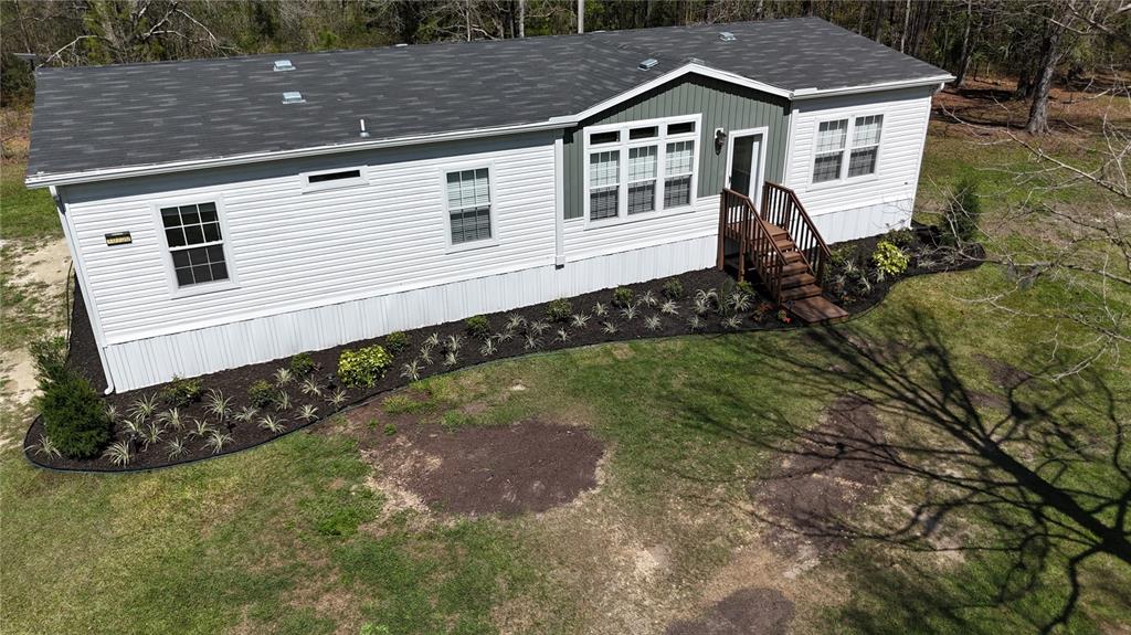 An aerial view of a white manufactured home with a dark roof and landscaped garden beds — 10750 NW 190TH STREET, MICANOPY, FL
