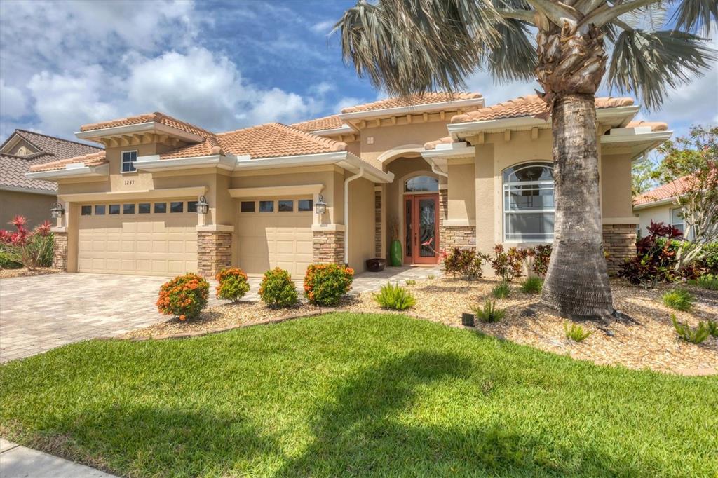 A single-story house with a tan stucco exterior, tile roof, and a two-car garage — 1241 CREEK NINE DRIVE, NORTH PORT, FL