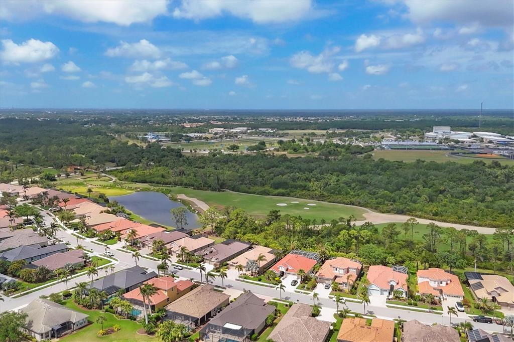 An aerial view shows a suburban neighborhood with houses bordering a golf course and pond — 1241 CREEK NINE DRIVE, NORTH PORT, FL