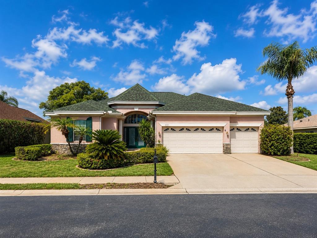 A single-story house with a green roof, pink stucco exterior, and a three-car garage — 2021 BLUE BEECH COURT, TRINITY, FL