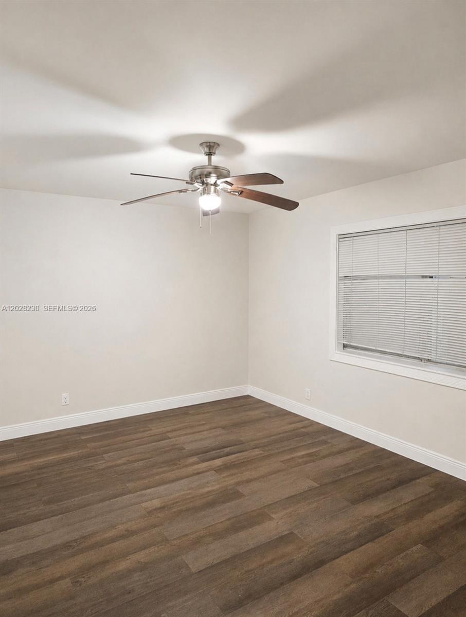 An empty bedroom features light-colored walls, dark wood-look flooring, and a ceiling fan — LAUDERHILL, FL