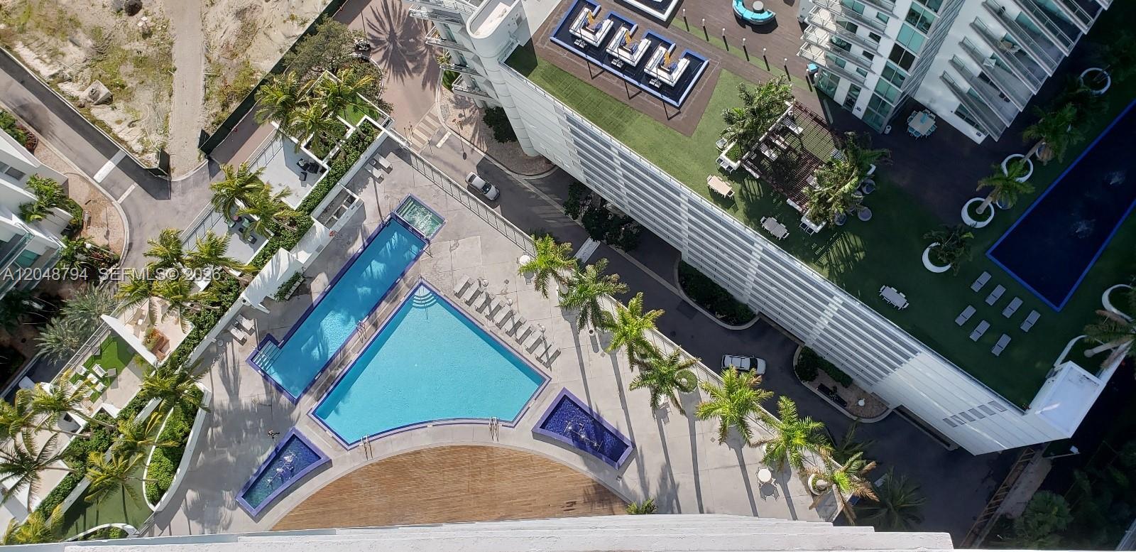 An aerial view shows a swimming pool complex with palm trees and a large building — 90 SW 3rd St # 3710, Miami FL 33130, MIAMI, FL